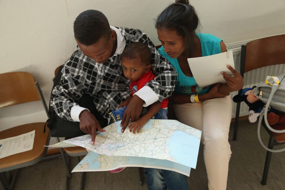 A young migrant couple from Eritrea look on a map of Europe as they prepare to depart with their son after they completed the registration process at a center for migrants at a facility of the German Federal Police (Bundespolizei) on August 31, 2015 in Rosenheim, Germany. (Sean Gallup/Getty Images)