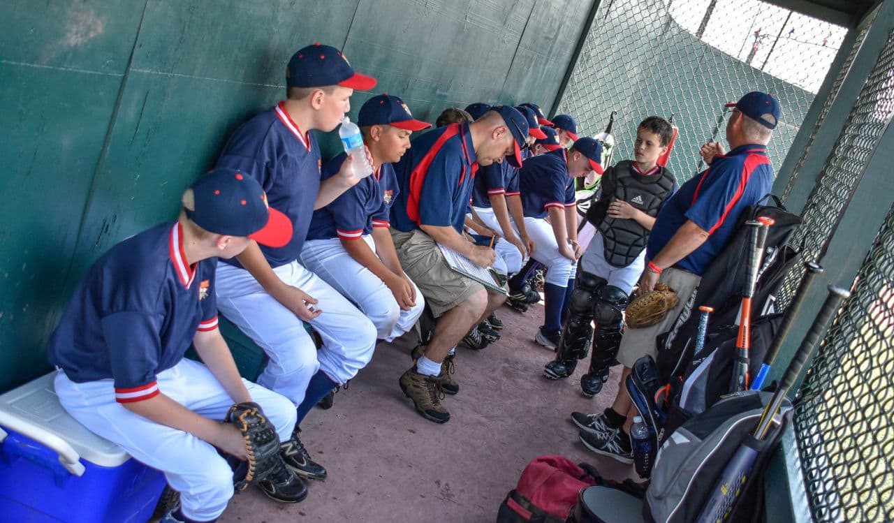 In the dugout minutes before first pitch, the author fills out the scorebook while Coach John Milewski prepares the Lions for their first game. (Alex Belisle/Courtesy)