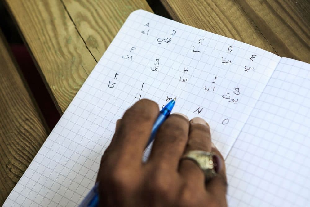 A refugee learns the letters of the German language taught by a volunteer in a garden of a private initiative near the refugee camp on August 29, 2015 in Dresden, Germany. Germany is expecting to receive 800,000 migrants this year and is struggling to cope with the record number. Germany is currently struggling to accommodate and process a record-number of asylum seekers from the Middle East, Africa and the Balkans. (Carsten Koall/Getty Images)