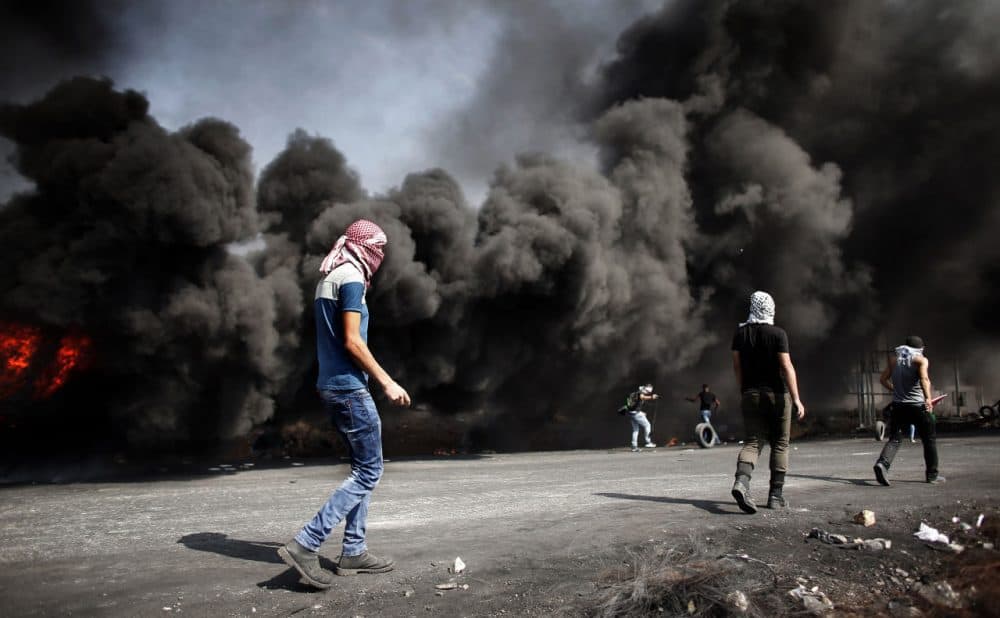 Palestinian demonstrators gather behind burning tires to throw stones towards Israeli security forces during clashes in the West Bank town of Al-Bireh, on the northern outskirts of Ramallah, on October 20, 2015. (Thomas Coex/AFP/Getty Images)