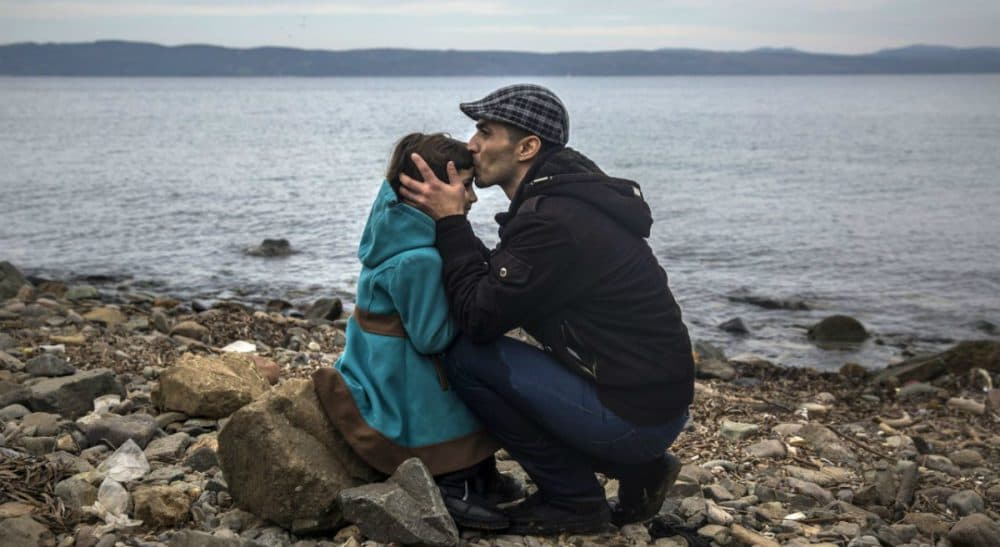 Eileen McNamara: "If they are not the embodiment of the promise engraved on the Statue of Liberty, who exactly are the 'huddled masses yearning to breathe free' that Emma Lazarus described?" In this photo, a Syrian man kisses his daughter shortly after disembarking from a dinghy at a beach on the Greek island of Lesbos, Monday, Nov. 16, 2015. (Santi Palacios/AP)