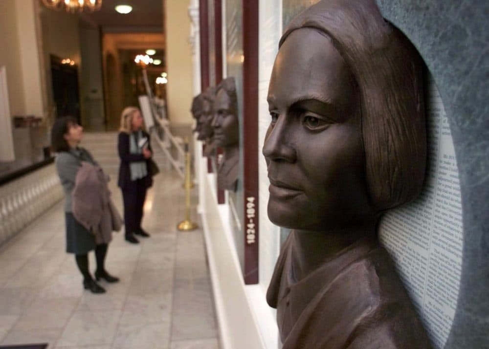 Guests view a work of art titled "Hear Us", featuring six bronze reliefs highlighting the contributions of women in public life in Massachusetts, at the Statehouse in Boston. In the foreground is the likeness of Lucy Stone (Charles Krupa/AP).