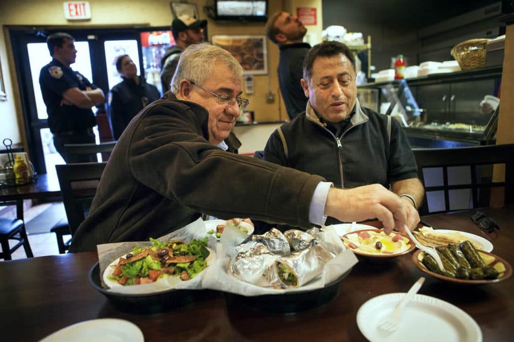 Camille Nasrah, left, and Salah Asfoura -- both Syrian nationals living in Worcester -- eat lunch at Bahnan’s International Marketplace. (Jesse Costa/WBUR)