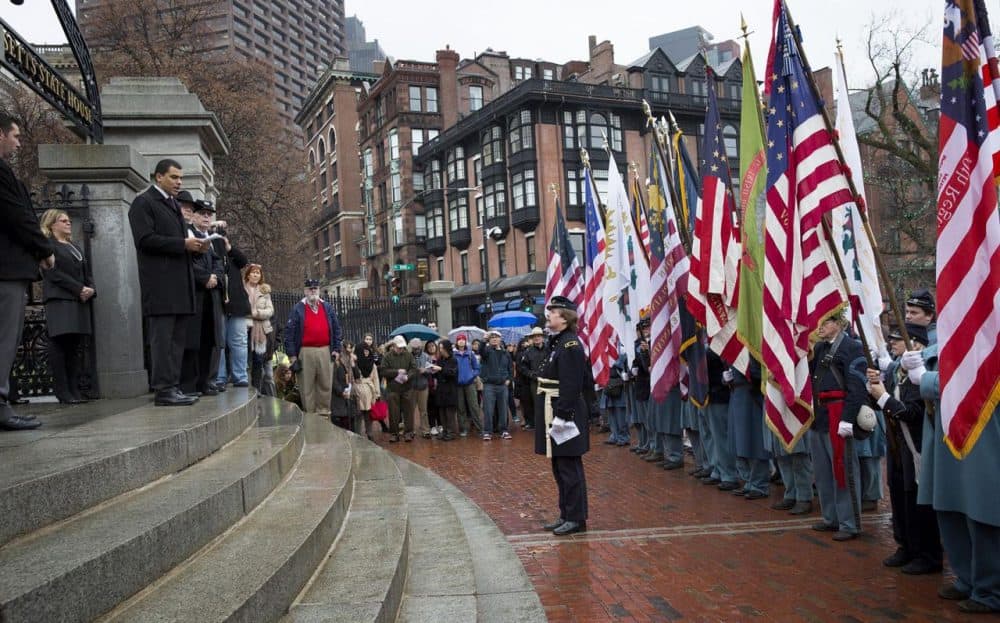 Secretary of Veterans' Services Francisco Urena welcomes flag bearers to the State House Tuesday to commemorate 150 years since the return of the state's Civil War battle flags. (Robin Lubbock/WBUR)