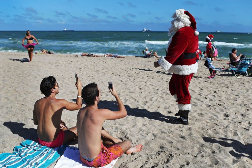 Timmy McGovern (dressed as Santa Claus) walks along the beach passing out candy canes and posing for pictures with beach goers on December 21 in Fort Lauderdale, Florida. Santa Claus has been visiting the beach just before Christmas for over 30 years. (Joe Raedle/Getty Images)