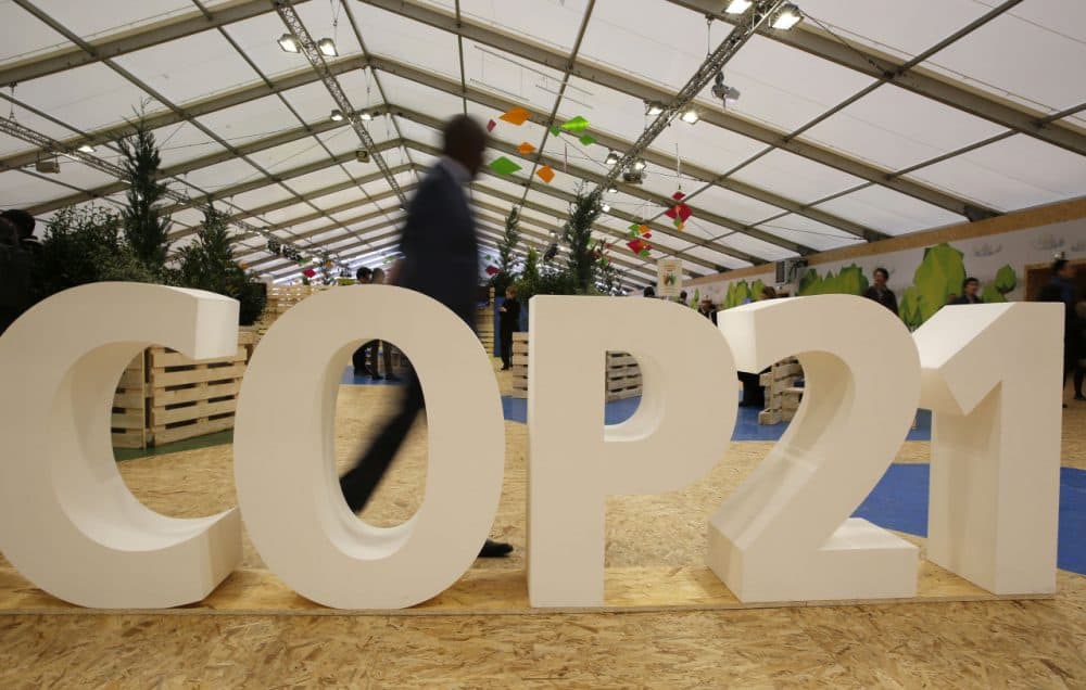 A majority of Massachusetts voters polled put the Paris terror attacks, the presidential election and, yes, the Patriots, higher on their list of interest than the big climate summit happening in France. Pictured here, a man walks past a display at COP21, the United Nations Climate Change Conference in France. (Christophe Ena/AP)