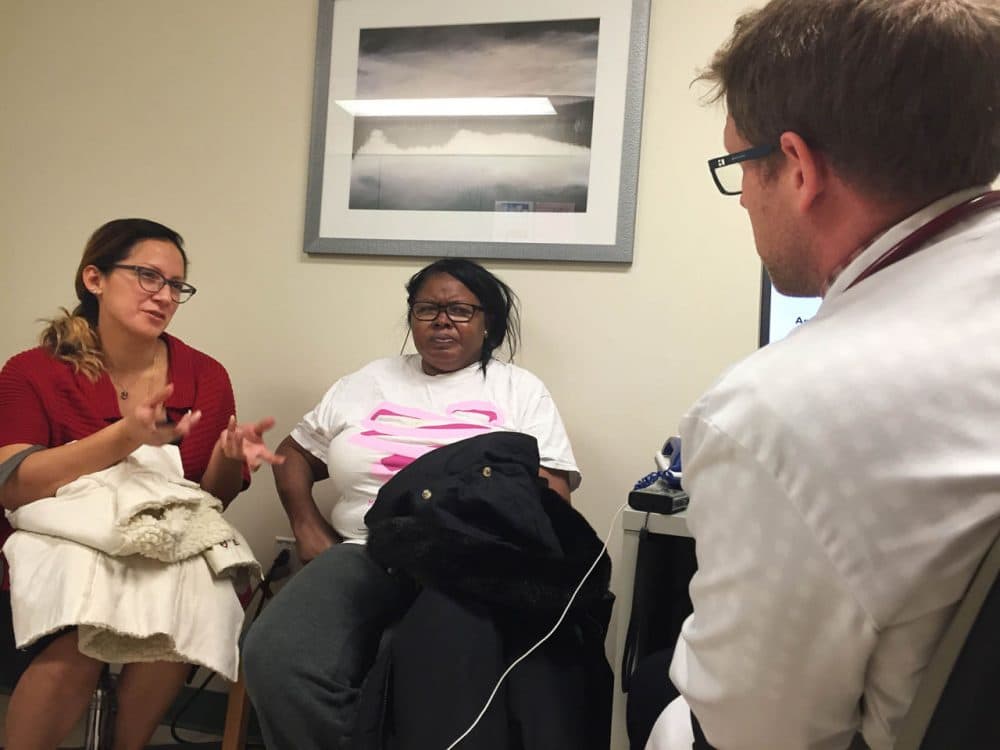 Guissela Mariluz, left, a community health worker at Rosie's Place in Boston, translates and negotiates a new plan for diabetes treatment for patient Luciana Joaquin with endocrinologist Dr. Devin Steenkamp. (Martha Bebinger/WBUR)