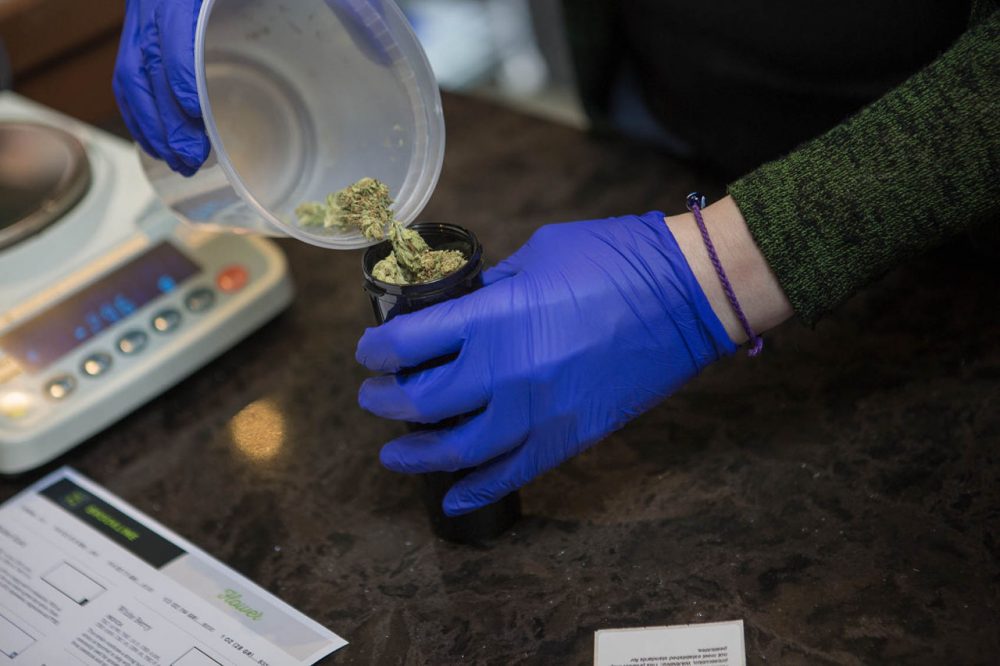 Patient Service Associate Ashley Cabana dispenses 14 grams (1/2 oz) of Facewreck marijuana flower for patient Sam Brown. (Jesse Costa/WBUR)