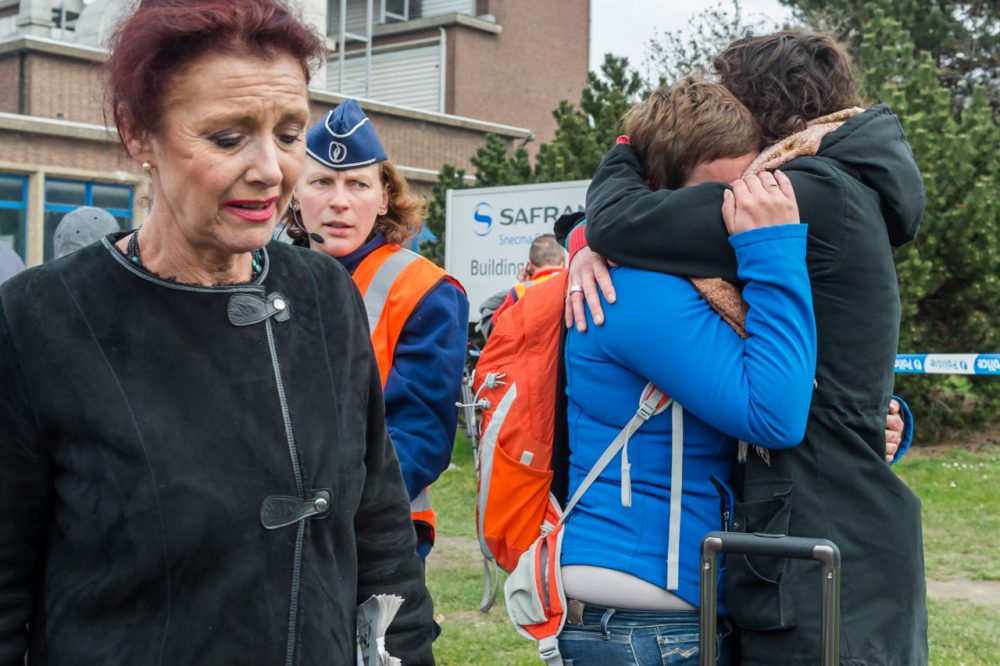 People react outside Brussels airport after explosions rocked the facility in Brussels, Belgium on Tuesday. (Geert Vanden Wijngaert/AP)