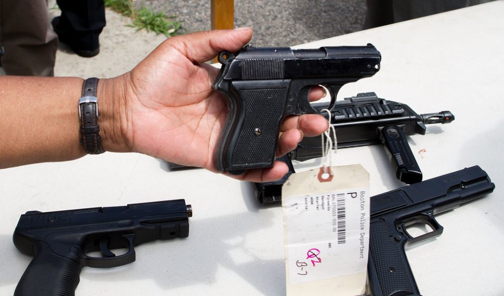 Audience members pick up toy guns put on display by the Boston Police Department at a gathering of Boston faith leaders on July 9th, 2015 calling attention to the potential dangers of toy or replica firearms. The new study out from BU on Thursday looks at how different state gun laws effect firearm mortality. (Hadley Green for WBUR)