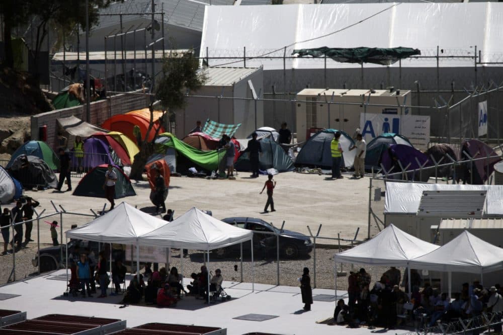 People sit under newly erected tents inside Moria camp on Lesbos island, Greece, where 2,300 migrants and refugees are being detained for deportation back to Turkey on Friday, April 15, 2016. Pope Francis will visit Moria camp Saturday, a mission human rights groups hope will highlight the plight of refugees who fled their war-ravaged homes only to be denied entry to Europe. Pope Francis will be joined by Ecumenical Patriarch Bartholomew and the head of the Orthodox Church of Greece, Athens Archbishop Ieronymos II. (Petros Giannakouris/AP)