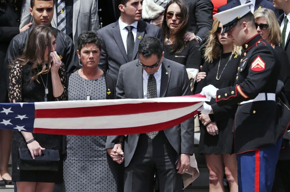 Linda Orlando, center, and her husband Richard Orlando pause as a flag is folded during a memorial ceremony for their son, U.S. Marine Cpl. Christopher Orlando, outside St. Paul's Church in Hingham Friday. (Charles Krupa/AP)