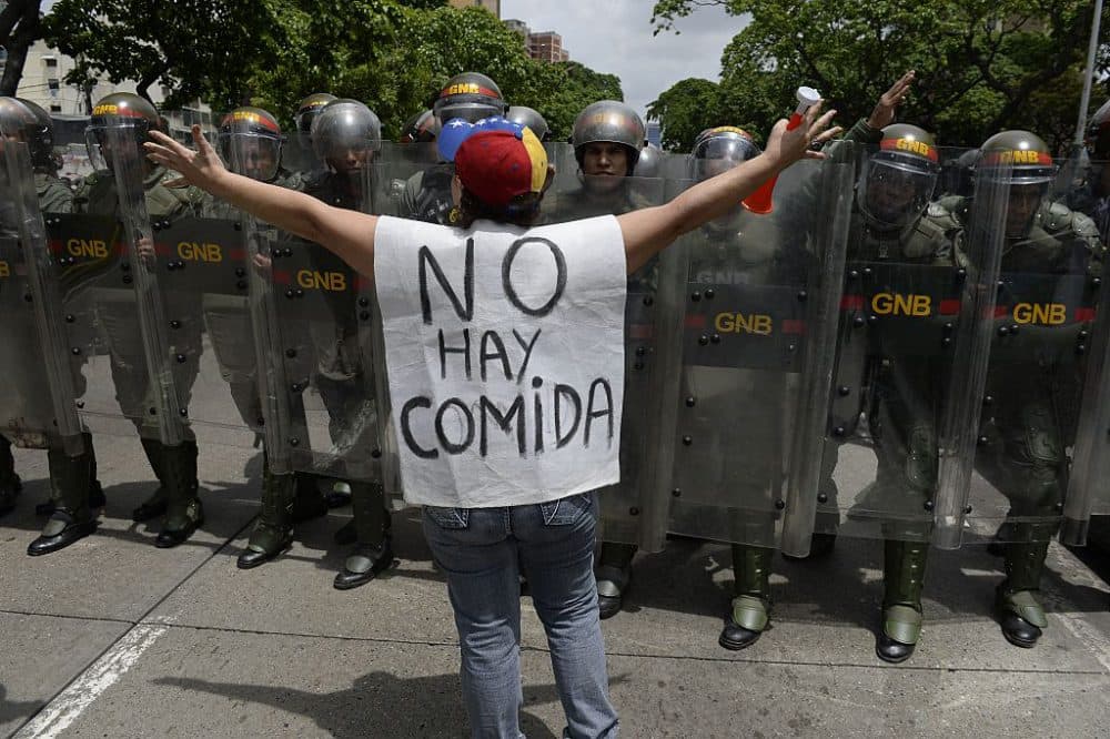 A woman with a sign reading "There is no food" protests against new emergency powers decreed this week by President Nicolas Maduro in front of a line of policemen in Caracas on May 18, 2016. (Federico Parra /AFP/Getty Images)