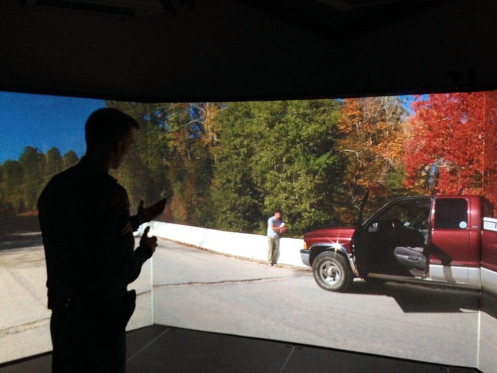 Washington State Patrol Corporal Brandon Dumont, an instructor at the Patrol's academy in Shelton, demonstrates de-escalation tactics while using a video simulator.
(Austin Jenkins/Northwest News Network)