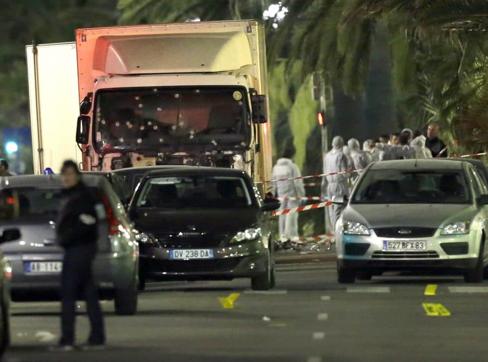 Forensic officers stand near a truck with its windscreen riddled with bullets, that plowed through a crowd of revelers who'd gathered to watch the fireworks in the French resort city of Nice, southern France, Friday, July 15, 2016. At least 80 people were killed before police killed the driver, authorities said. (Claude Paris/AP)