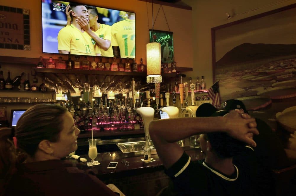 Camila Ornelas, left, and Vander Junior, right, both originally of Brazil, watch a televised soccer match between Brazil and Denmark at the Rio Olympics on Wednesday while sitting at the bar in the Tropical Cafe, in Framingham, Mass. (Steven Senne/AP)
