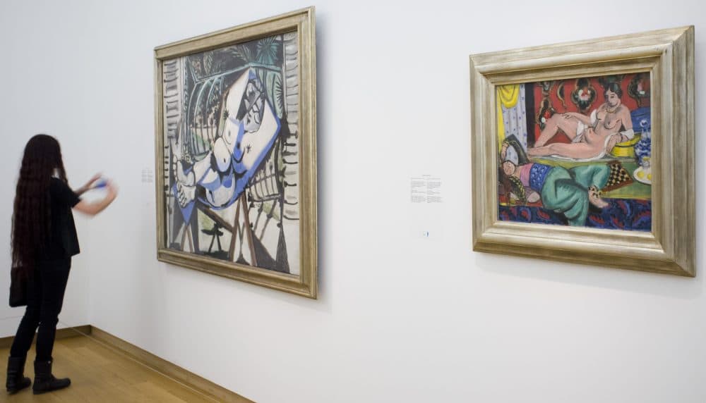 A woman takes a pictures of a painting titled "Two Odalisques, One Undressed, Ornamental Background and Checkerboard" dated 1928 by French artists Henri Matisse (1869-1954), right, next to a painting by Pablo Picasso titled "Nude in front of a Garden," left, during a press preview of the exhibit "The Oasis of Matisse" at Stedelijk Museum in Amsterdam, Netherlands in 2015. (Peter Dejong/AP)