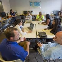 Entreprenuers, mentors and staff collaborate in the Entreprenuership for All co-working space in Lawrence. (Jesse Costa/WBUR)