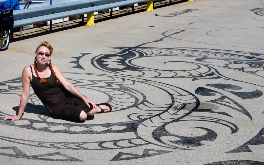 Artist Liz LaManche sits on her &quot;Connected by Sea&quot; installation on the dock of the East Boston Shipyard. (Amy Gorel for WBUR)