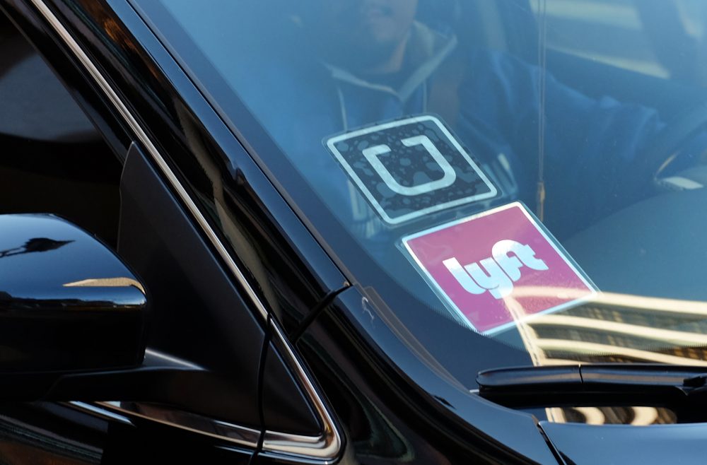A driver displaying Lyft and Uber stickers on his car (Richard Vogel/AP)