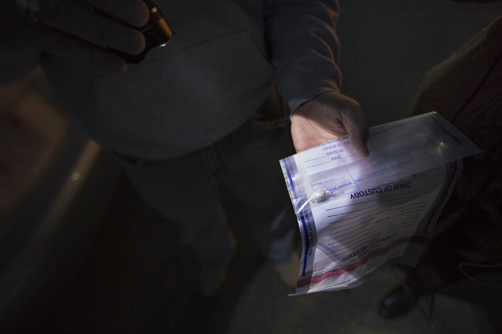 An undercover police detective holds an evidence bag containing what is believed to be one gram of heroin, which is worth about $100 in the Framingham/Natick area. (Jesse Costa/WBUR)