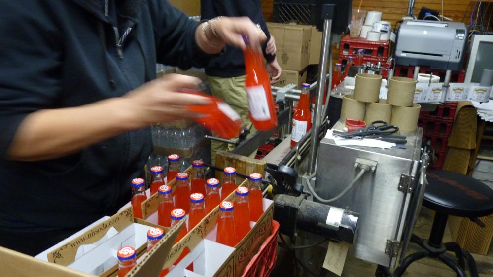 Bottles of Squamscot Soda get a label inside the company's factory in Newfields, N.H. (Todd Bookman/NHPR)