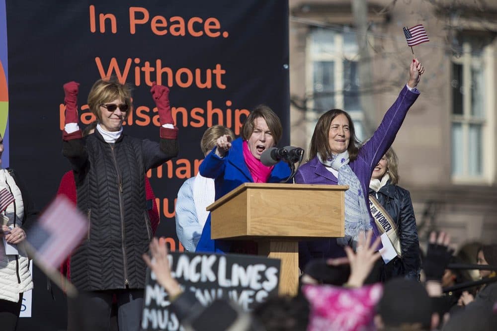 Attorney General Maura Healey calls out to the crowd as Auditor Suzanne Bump and Treasurer Deb Goldberg cheer. (Jesse Costa/WBUR)
