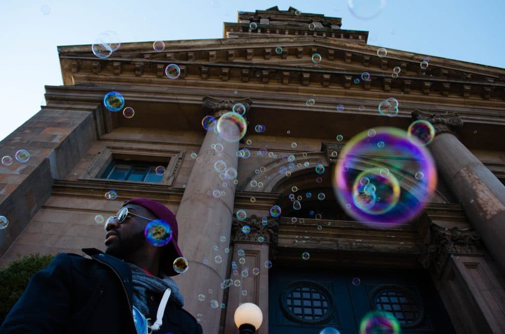 "My last name is Civil, like civil rights," says Gaetan Civil as he sits outside the Arlington Street Church watching the march pass. (Elizabeth Gillis/WBUR)