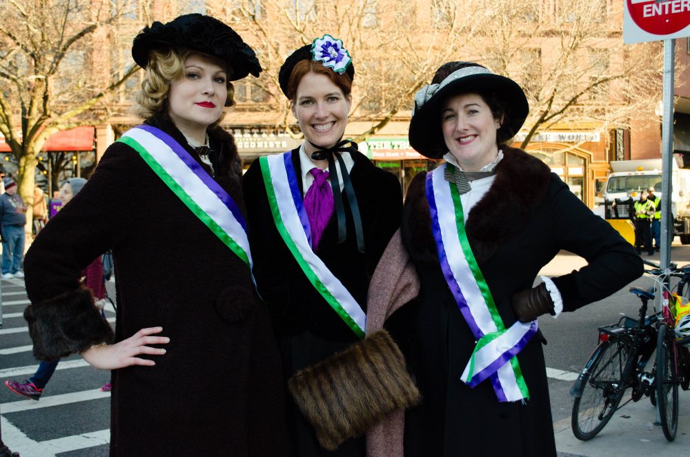 "Vintage enthusiasts" Sarah Kruse, from Providence, Laura Grzybowski, of Newton, and Brooke Steinhauser, of Amherst, dressed as suffragettes for the march. (Elizabeth Gillis/WBUR)