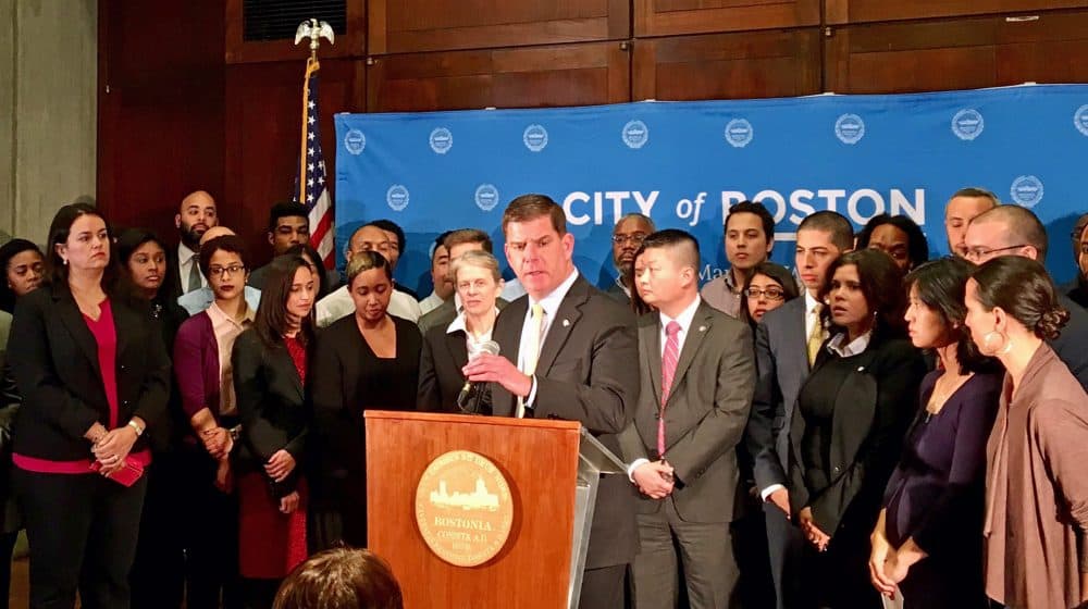 The Safe Communities Act would keep state and local police out of immigration enforcement, writes Karen Pita Loor, allowing them to focus on enforcing Massachusetts criminal law. Pictured: Surrounded by members of his administration and state lawmakers, Mayor Marty Walsh announced Boston will maintain its status as a "sanctuary city." (Shannon Dooling/WBUR)