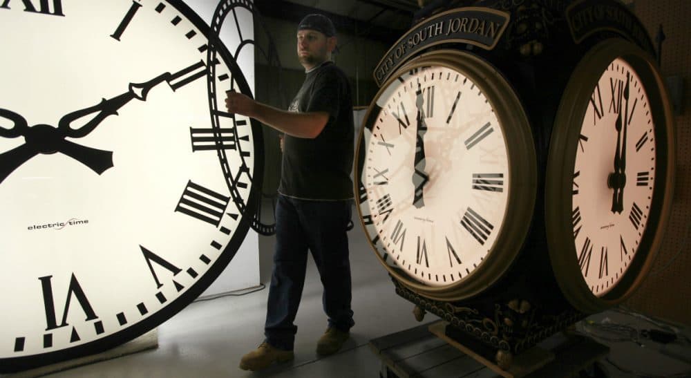 In this 2011 photo, Dan LaMoore of Electric Time Company moves a clock face at the company's plant in Medfield. (Elise Amendola/AP)