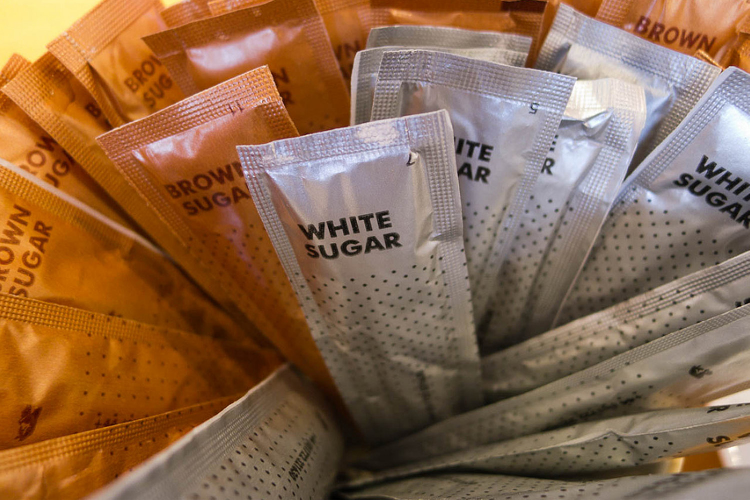 A collection of brown and white sugar packets. 