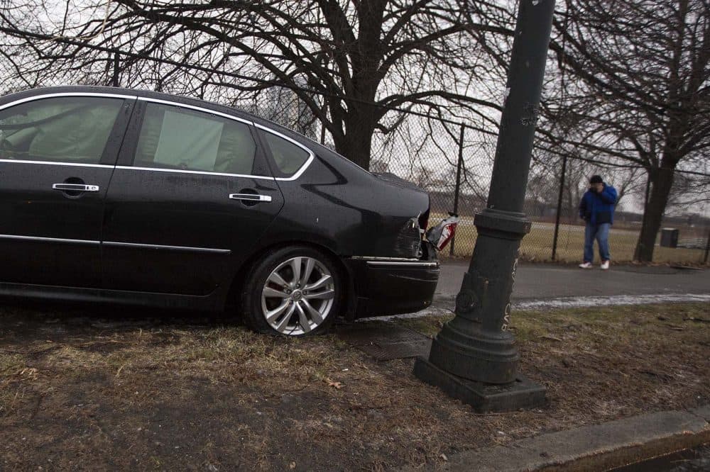 A driver is on the phone calling for assistance after a car accident due to the icy road conditions Wednesday morning on Memorial Drive in Cambridge. (Jesse Costa/WBUR)