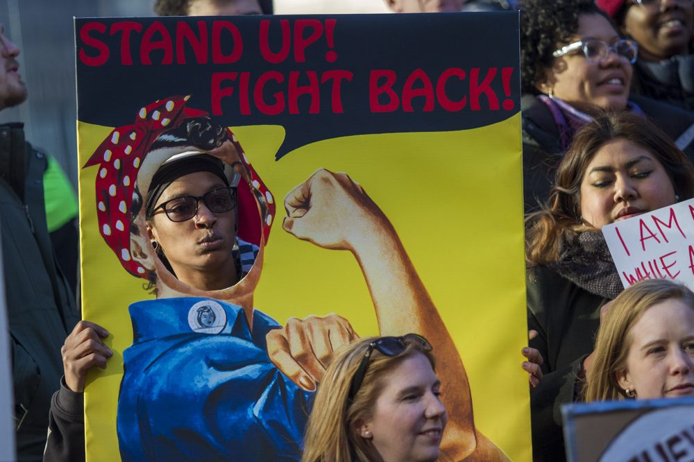 Quiana Ferguson sticks her head through a cardboard cut-out copy of the iconic Rosie the Riveter "We Can Do It" poster. (Jesse Costa/WBUR)