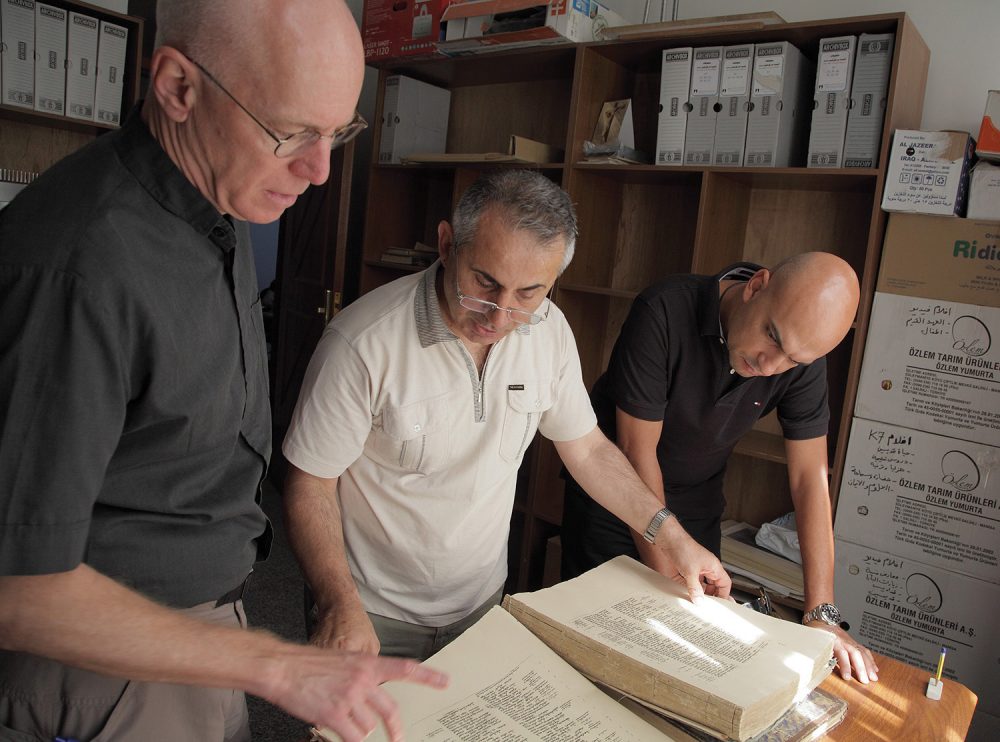 Father Columba Stewart (left), Father Nageeb Michael (center) and Walid Mourad examine a printed Bible at the Dominican Priory in Qaraqosh, Iraq.  (AP Photo/Courtesy Hill Museum & Manuscript Library)