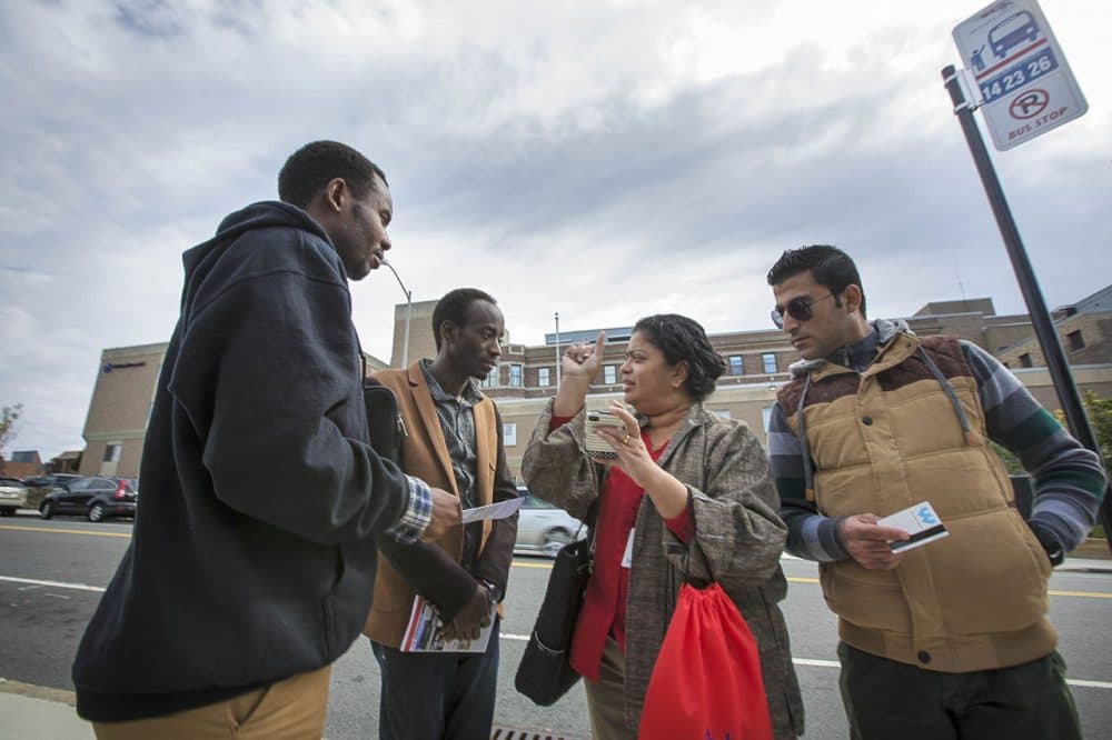 Ascentria Care Alliance, a resettlement agency based in Worcester, announced Monday that as a result of Trump's travel ban it had laid off or reduced hours for 14 employees. In this 2015 photo, an Ascentria instructor shows clients when the next WRTA bus will arrive using a smartphone app.  (Jesse Costa/WBUR) 