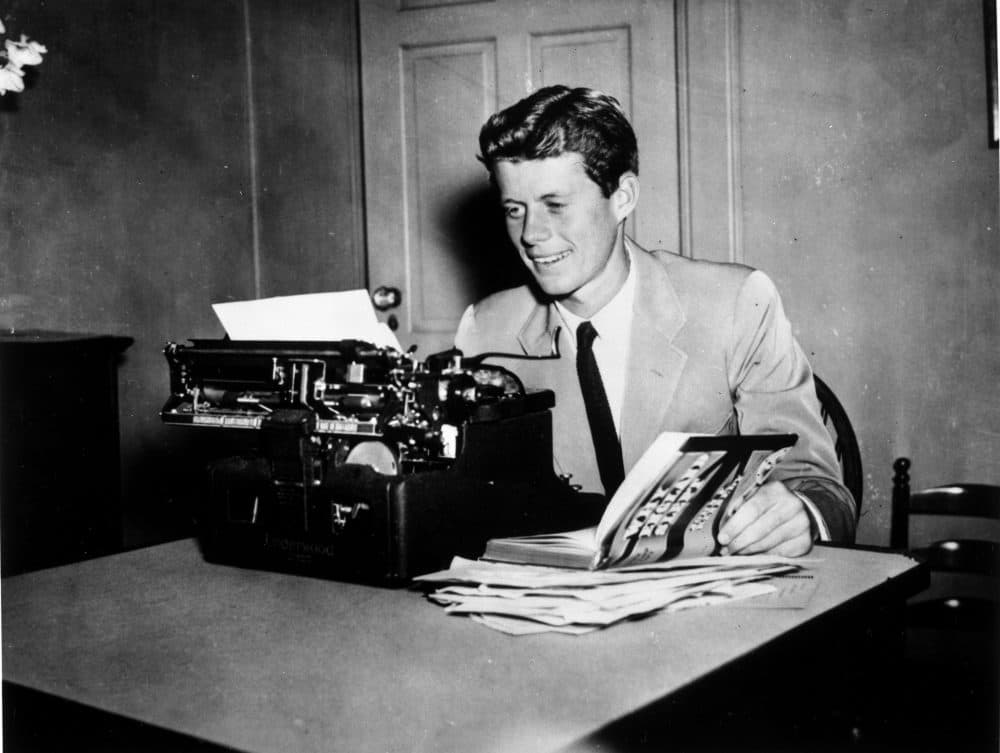 John F. Kennedy aan een schrijfmachine met zijn boek "Why England Slept." Het boek begon als een erescriptie getiteld "Appeasement in München." (John F. Kennedy Presidentiële Bibliotheek)"Why England Slept." The book began as an honors thesis titled "Appeasement at Munich." (John F. Kennedy Presidential Library)