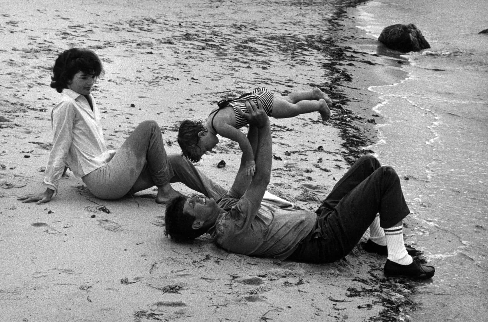 Jacqueline Bouvier Kennedy and John F. Kennedy, who is holding Caroline Kennedy, on a beach in Hyannis Port, Mass. (Courtesy Mark Shaw/John F. Kennedy Presidential Library and Museum in Boston)