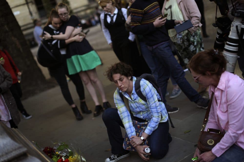 To write the Manchester suicide bomber off as a coward or a loser flattens a human being whose dimensionality we must better understand, writes Julie Wittes Schlack. Pictured: People stand next to flowers after a vigil in Albert Square, Manchester, England, Tuesday May 23, 2017, the day after the suicide attack at an Ariana Grande concert that left 22 people dead. (Emilio Morenatti/AP)