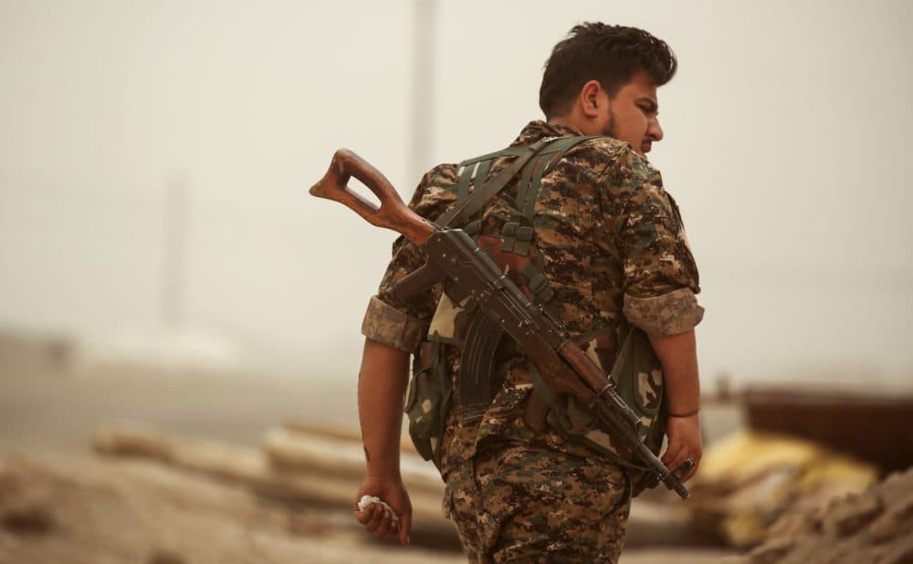 A member of the Kurdish People's Protection Units (YPG) walks with a Kalashnikov assault rifle in the town of al-Karamah, 26 kilometers from the Islamic State group bastion of Raqqa, on May 10, 2017. (Delil Souleiman/AFP/Getty Images)
