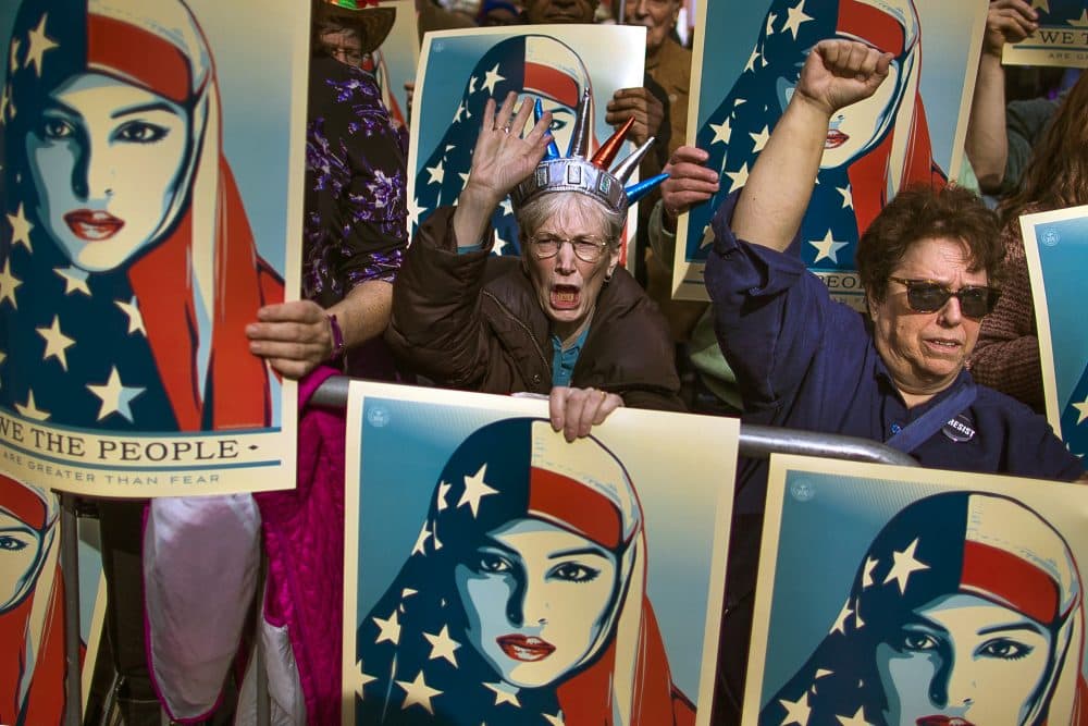 On Feb. 19, 2017, people carry posters during a rally against President Donald Trump's first executive order banning travel from seven Muslim-majority nations, in New York's Times Square. (Andres Kudacki/AP)