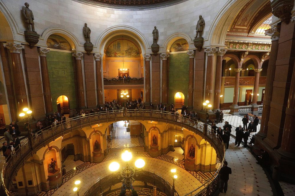 On Tuesday, during an unusual Independence Day session, state senators passed legislation that would end Illinois' record-setting budget impasse. Pictured: Lawmakers, lobbyists and visitors stand along the "Brass Rail" outside the House chambers during veto session at the Illinois State Capitol Thursday, Dec. 1, 2016, in Springfield, Ill. (Seth Perlman/AP)