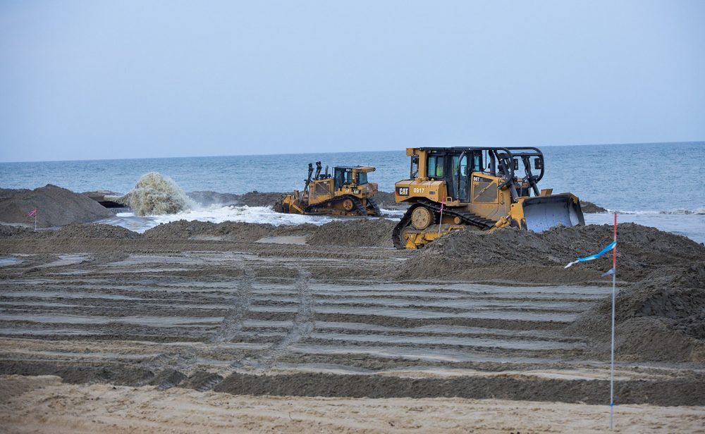 na plaży Buxton Buldożery przenoszą piasek z pogłębiarki 2 mile od brzegu. Ten tak zwany Projekt "odżywienia plaży" będzie kosztował ponad 7 milionów dolarów za milę, łącznie 22 miliony w publicznych pieniądzach. Inżynierowie gwarantują żywotność pięciu lat, ale Stan Riggs mówi, że piasek Zwykle zniknął w dwóch. (Jesse Costa / WBUR)