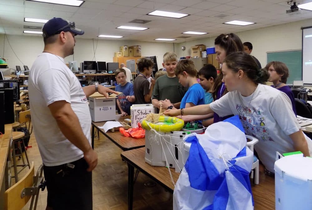 Southwest Community College Balloon team leader Jesse Moore shows middle schoolers a deflated balloon and payload the team launched during a practice run. (Helen Chickering/Blue Ridge Public Radio)