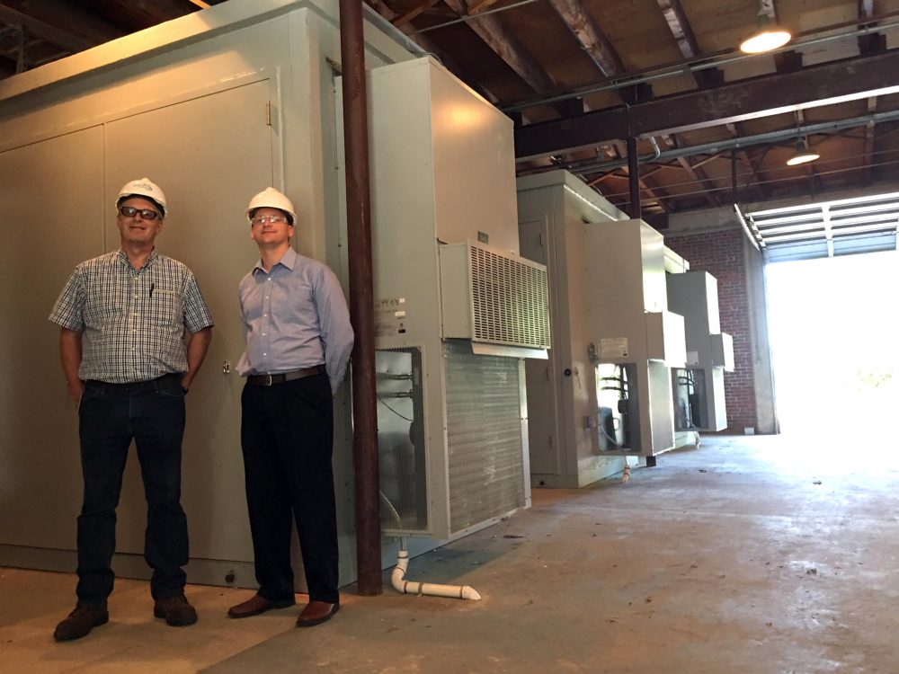 NextEra site manager Ben Pierce and project manger Jeff Plew at the company's new "grid-scale" battery array on Cousins Island in Maine's Casco Bay. (Fred Bever/Maine Public)