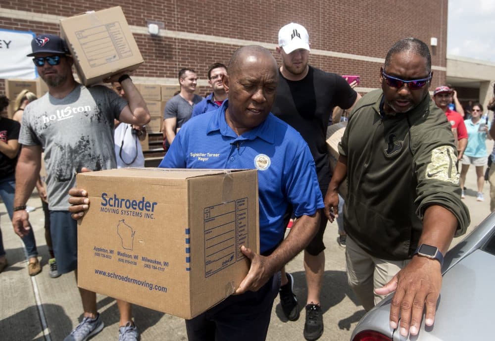 Houston Mayor Sylvester Turner, center, with Houston Texans Shane Lechler, left, and J.J. Watt, second right, distribute relief supplies to people impacted by Hurricane Harvey on Sept. 3 in Houston. (Brett Coomer/Houston Chronicle via AP, pool)