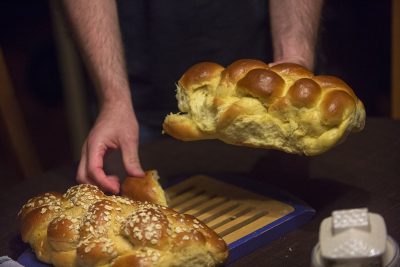 The breaking of the Challah bread before dinner as Susie and Rob's house. (Jesse Costa/WBUR)