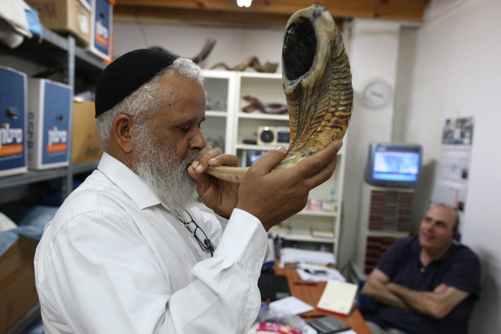 A Jewish man tests the sound of a shofar, a religious musical instrument made from a ram horn, before buying it at a Shofarot factory in Tel Aviv on Sept. 25, 2016, ahead of the Jewish New Year. (Menahem Kahana/AFP/Getty Images)