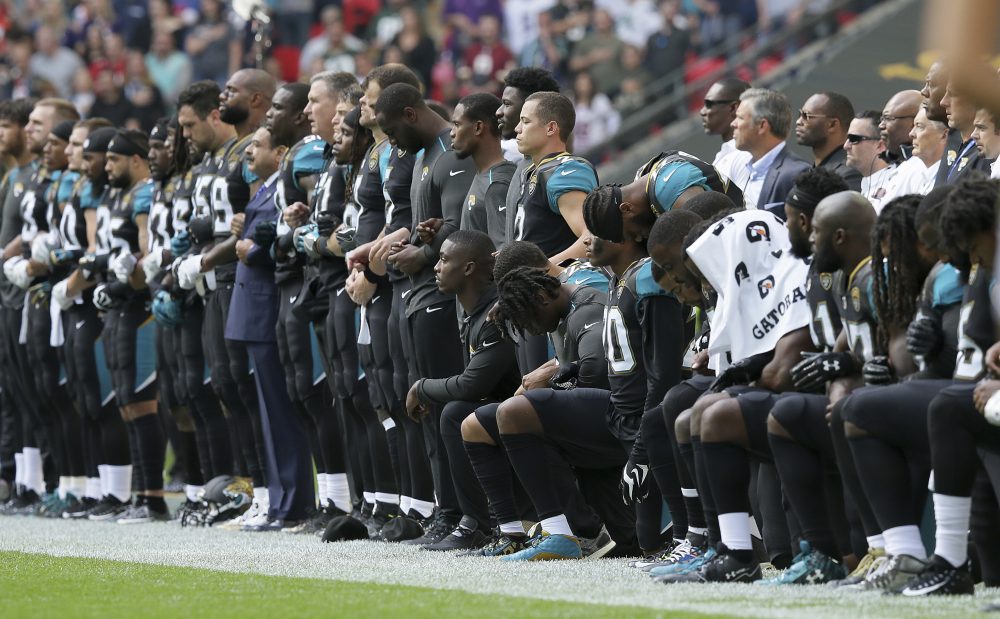 Jacksonville Jaguars players lock arms and kneel down during the playing of the U.S. national anthem before an NFL football game against the Baltimore Ravens at Wembley Stadium in London, Sunday Sept. 24, 2017. (AP Photo/Tim Ireland)