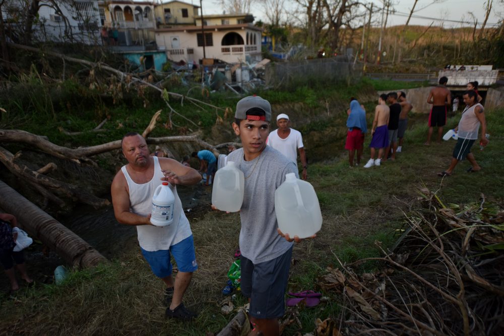 People carry water in bottles retrieved from a canal due to lack of water following passage of Hurricane Maria, in Toa Alta, Puerto Rico, on Sept. 25, 2017. (Hector Retamal/AFP/Getty Images)